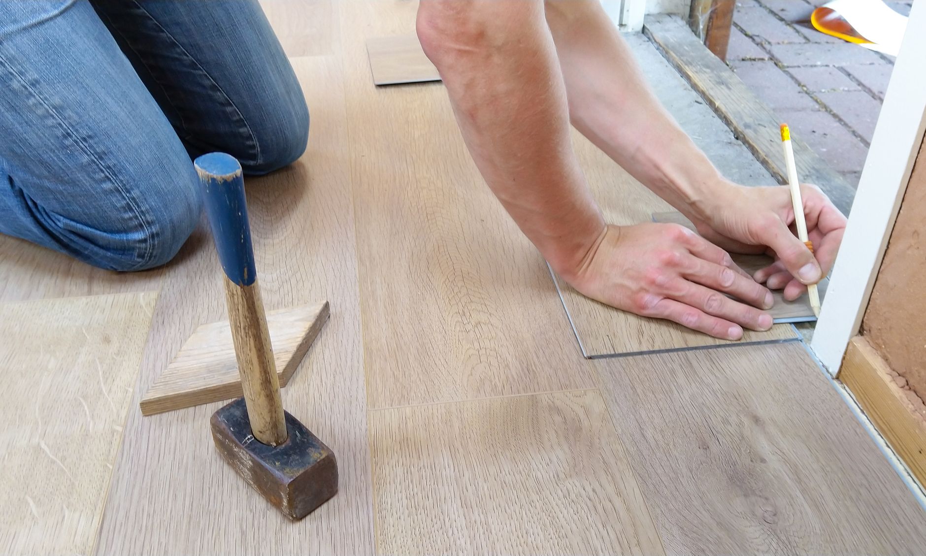 Handwerker misst und markiert Holzdielen vor dem Verlegen